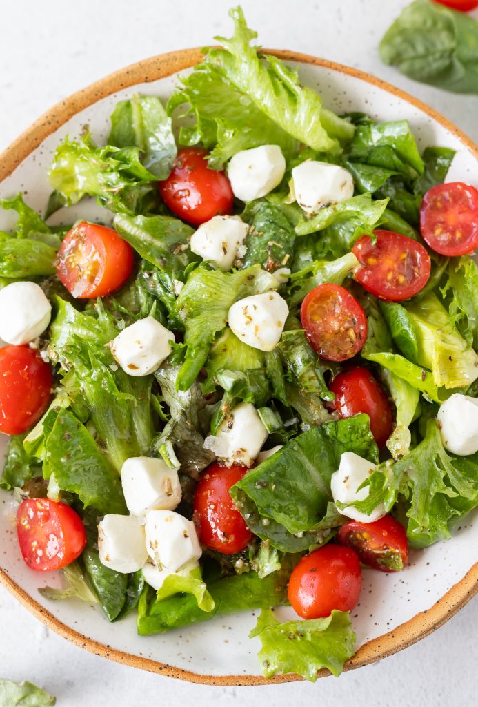 lettuce, mozzarella balls, tomatoes and basil in bowl