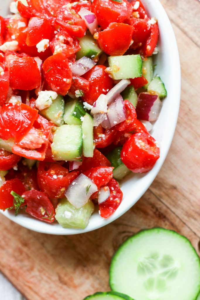 chopped tomatoes cucumbers and onion in white dish